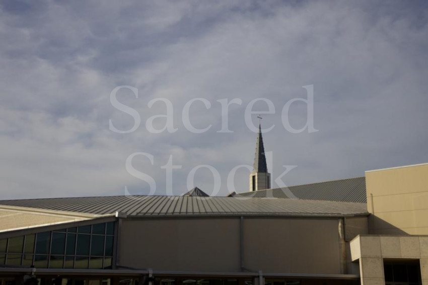 Steeple against roof and clouds